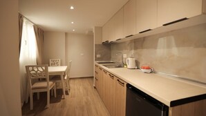 Une cuisine compacte avec un coin repas, comprenant un évier, une bouilloire et un lave-vaisselle.