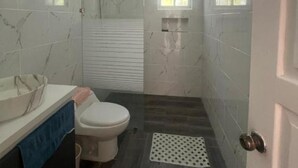 Un baño pequeño con inodoro, lavabo y zona de ducha.