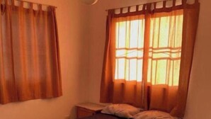 Un dormitorio con cama, cortinas, ventilador de techo y mesita de noche.