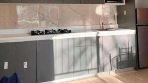 Una cocina moderna con gabinetes grises, microondas integrado y un refrigerador de acero inoxidable.