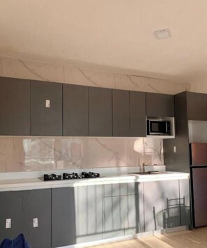 A modern kitchen with grey cabinets, a built-in microwave, and a stainless steel refrigerator. - apartment for rent (Bayahíbe)