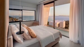 A modern bedroom with a large bed, a view of the sea, and a balcony.