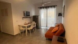 A modern living room with a dining area, a sofa, a TV, and a ceiling fan. - apartamento con piscina (Bayahíbe)