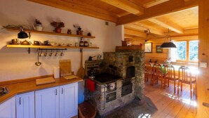 Een gezellige keuken met een stenen open haard, houten planken en een zithoek met stoelen.