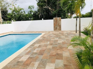 A swimming pool with a tiled deck and a white wall in the background. - Marvelous 1-bedroom apartment with AC in Bayahíbe (Bayahíbe)