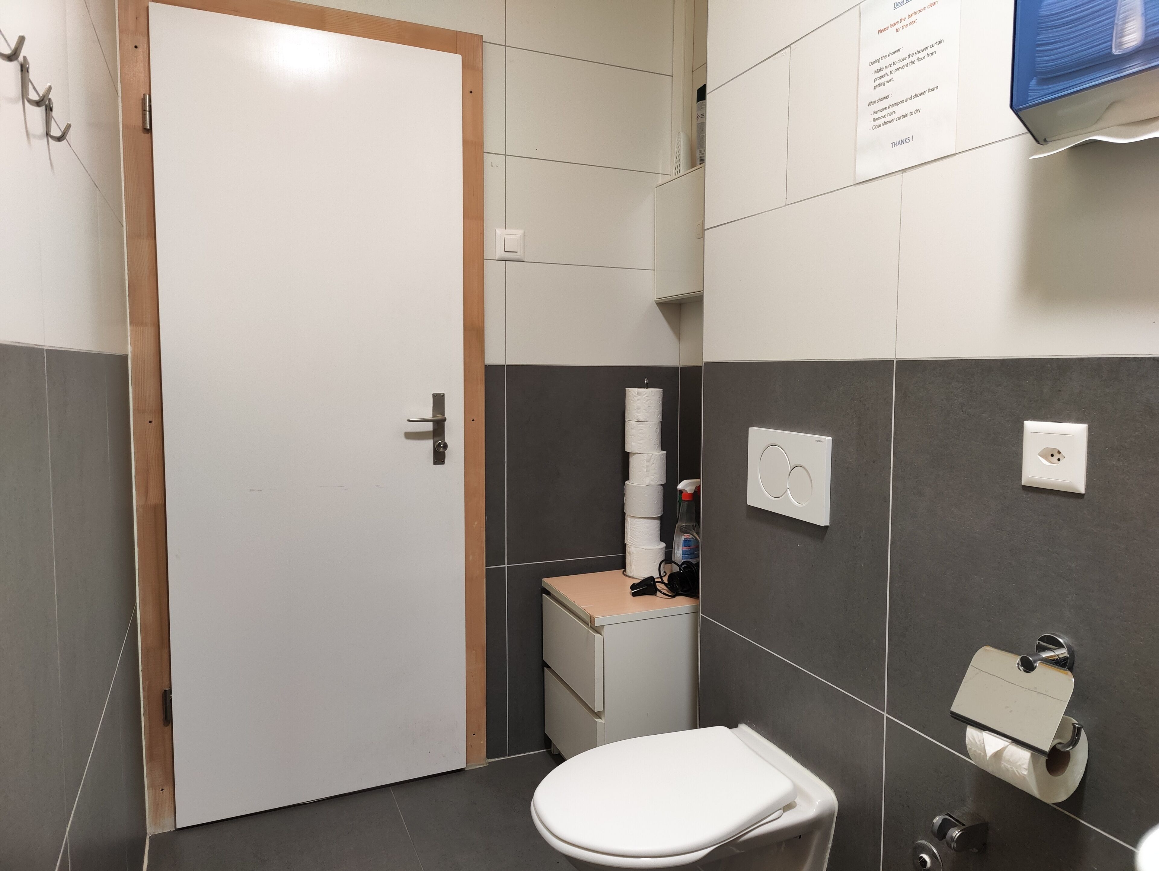 A small, clean bathroom with a toilet, a sink, and a towel dispenser.