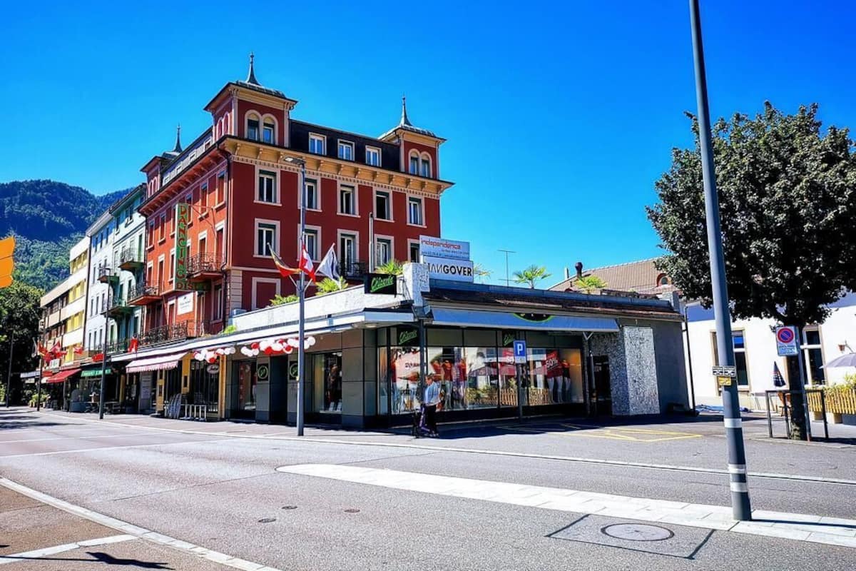 Vista de la calle con un edificio rojo que tiene un letrero de 'Café' y un escaparate con un letrero de estacionamiento 'P'.