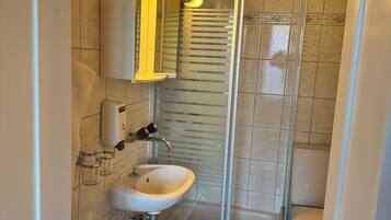 A modern bathroom with a white sink, mirror, and glass shower enclosure.