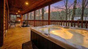 Eine Holzterrasse mit Whirlpool, Stühlen und einem Fernsehbildschirm.