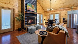 Ein gemütliches Blockhaus-Interieur mit Kamin, Ledersofa, Essbereich und Küche.