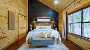 Ein Schlafzimmer einer Holzhütte mit einem Bett, einer Bank, einem Fenster und einer Deckenleuchte.