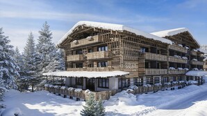 A multi-story wooden building with balconies, surrounded by snow-covered trees. - Apartment mit 1 Schlafzimmer (Kaprun)