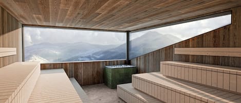 A modern sauna room with wooden walls and a large window offering a mountain view.