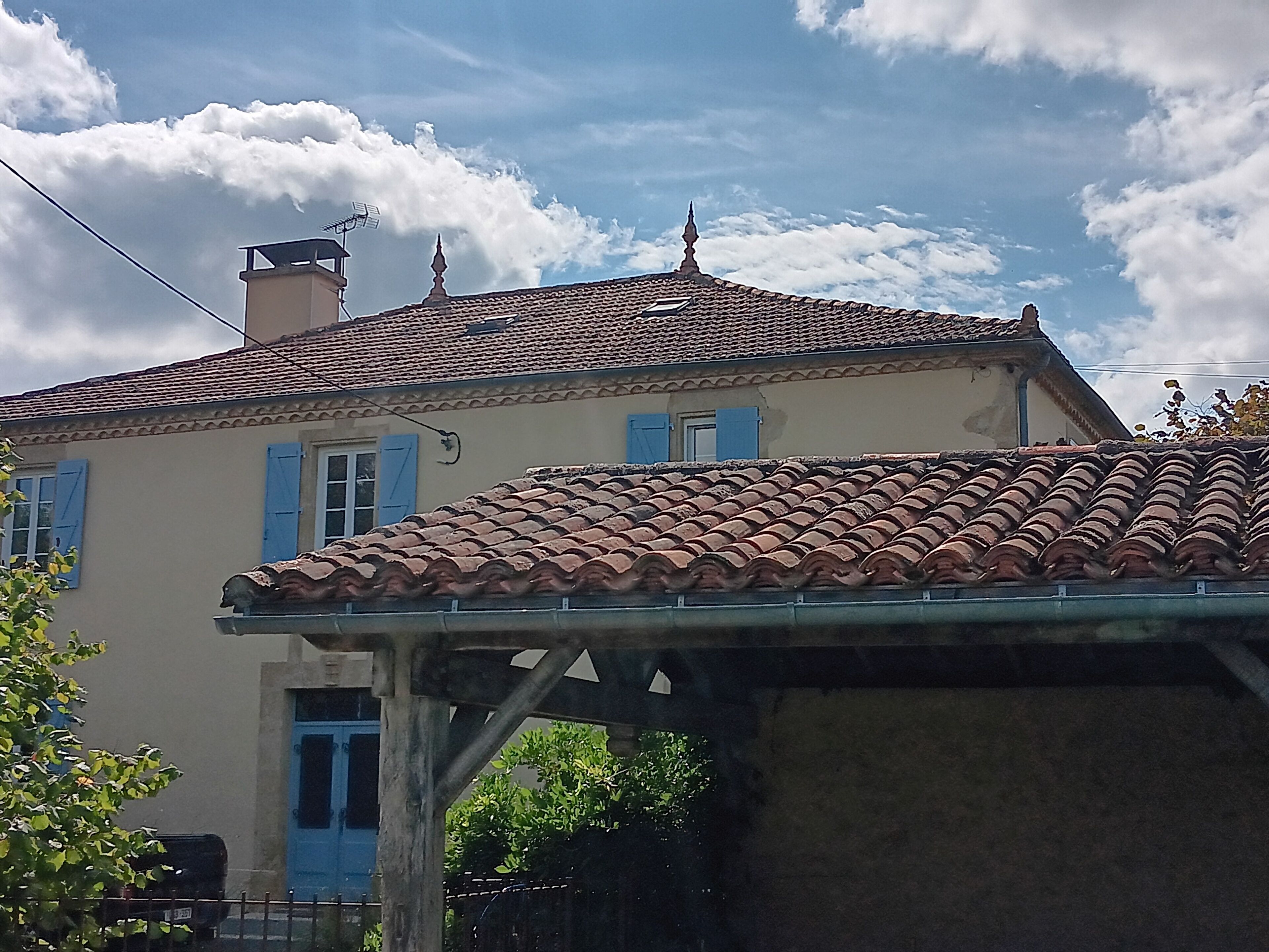 A house with a tiled roof, a chimney, and blue shutters.