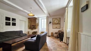 Een woonkamer met een bank, een salontafel, een lamp en een open haard.
