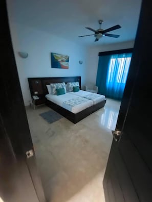 Ein Schlafzimmer mit einem Bett, einem Deckenventilator und einem Fenster mit Vorhängen.