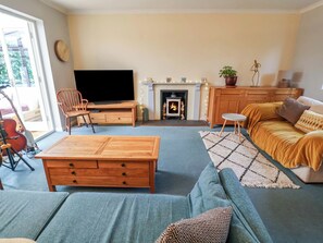 A cozy living room with a flat-screen TV, a fireplace, a sofa, and a coffee table.