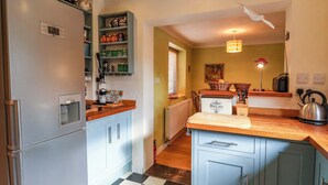 Eine Küche mit Kühlschrank, Kaffeemaschine, Brotbackmaschine und Wasserkocher auf der Arbeitsfläche.