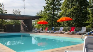 Une piscine avec des chaises longues et deux parasols orange.