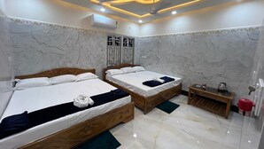 Habitación de hotel con dos camas de madera, paredes de mármol e iluminación empotrada en el techo.