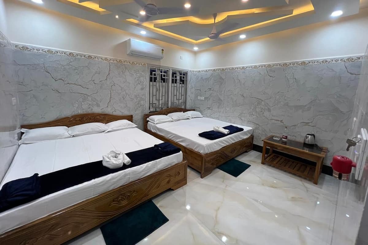 A hotel room with two wooden beds, marble walls, and a ceiling with recessed lighting.