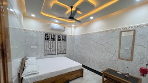 Un dormitorio con cama, mesita de noche de madera, espejo y ventilador de techo.