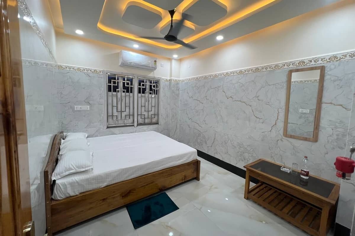 A bedroom with a bed, a wooden bedside table, a mirror, and a ceiling fan.