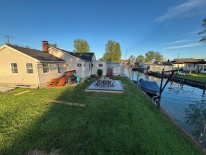 Ein Wohngebiet mit einer Rasenveranda, einem kleinen Boot, das an einem Kanal liegt, und Häusern im Hintergrund.
