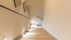 A staircase with beige tiles, handrails, and framed pictures on the walls.