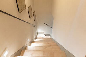 Una escala amb rajoles beix, baranes i quadres a les parets.