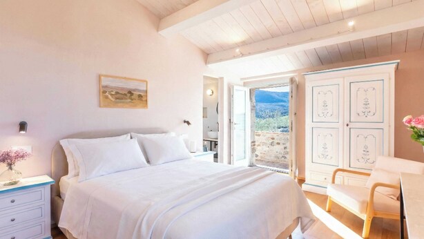 A bedroom with a bed, bedside table, and a view of the outdoors.