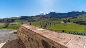 A stone wall with a view of a green landscape and distant mountains.