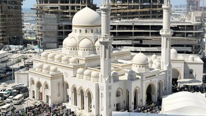 Una gran mezquita con múltiples cúpulas y minaretes, rodeada de edificios urbanos y obras en construcción.
