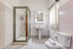 A bathroom with a glass-enclosed shower, a pedestal sink, and a toilet. - Ta Frenc Apartments - 2 BDR, 1 BTH (L-Għasri)