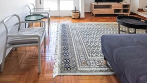 Una sala de estar moderna con un sofá, un televisor y un comedor con sillas y una mesa.