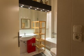 A modern bathroom with a white sink, a red cabinet, a wooden shelving unit, a mirror, and a bathtub. - ACROPOLITANA 2 (near Acropolis and museum) (Athina)