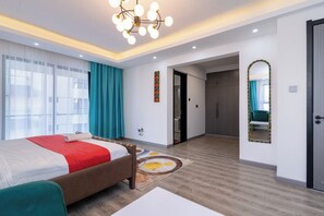 Een moderne hotelkamer met een groot bed, een kroonluchter, een spiegel en uitzicht over de stad.