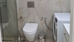 Ein Badezimmer mit Toilette, Bidet, Dusche und einer Waschmaschine.