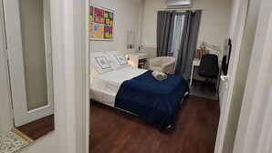 Ein Hotelzimmer mit Bett, Schreibtisch, Klimaanlage und einem fensterbepflanzten Fenster.