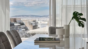 A modern room with a view of a cityscape, a table with a book and a lamp, and a potted plant. - September Athens Residences (Athens)