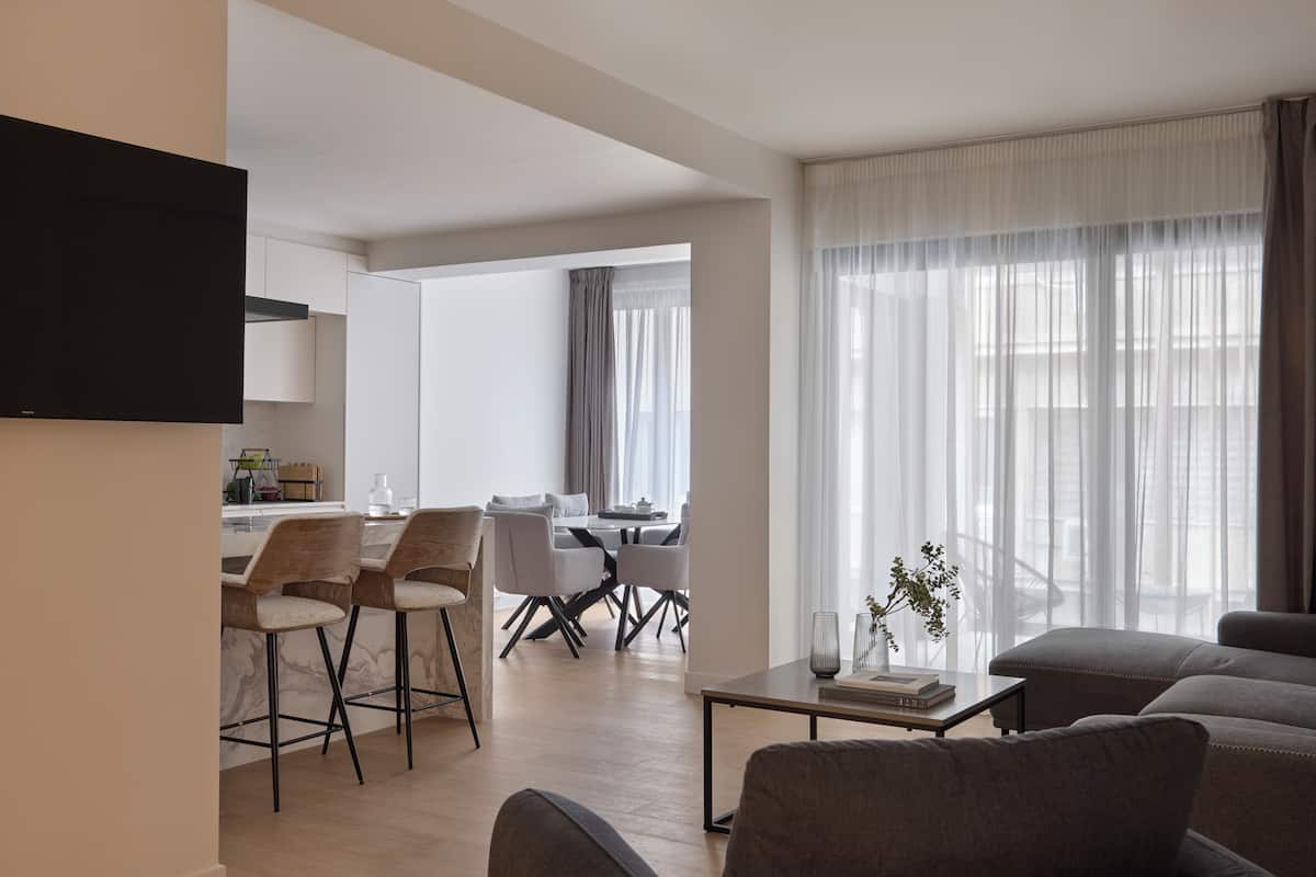 A modern living room with a sofa, a coffee table, and a dining area with chairs and a table.