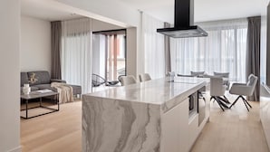 A modern living space with a marble island, a black range hood, and a dining area with chairs. - September Athens Residences (Athens)