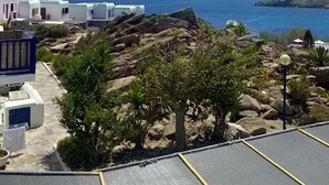 A coastal view with white buildings, rocky terrain, and a clear blue sky. - Smart  4 pers. apar. in Costa Ilios resort Myconos (Mikonos)
