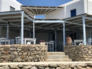 A covered outdoor seating area with stone steps leading to a building entrance. - Smart  4 pers. apar. in Costa Ilios resort Myconos (Mikonos)