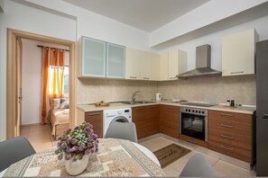 A compact kitchen with wooden cabinets, a built-in oven, and a washing machine.