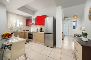 A modern kitchen with a stainless steel refrigerator, wooden cabinets, and a dining area with a glass table and chairs. - Levanta Cozy One-Bedroom Apartment in Kalavarda (Kalavarda)