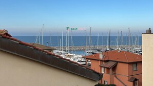 Ein Hafen mit mehreren vertäuten Booten, einem klaren Himmel und einem Gebäude mit dem Schriftzug "GIANSERENI".
