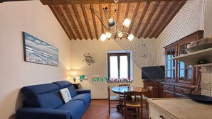 Ein gemütliches Wohnzimmer mit einem blauen Sofa, einem Esstisch mit Stühlen, einer Kandelaber und einer Küchenzeile mit Fliesenrückwand.
