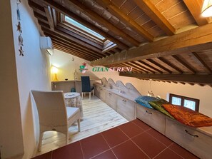 A cozy room with a wooden ceiling, a dining area with a table and chairs, and a bed with a colorful blanket. - 2 bedroom apartment for 4 people in a central area-Rif. Il sogno del Marinaio (San Vincenzo)