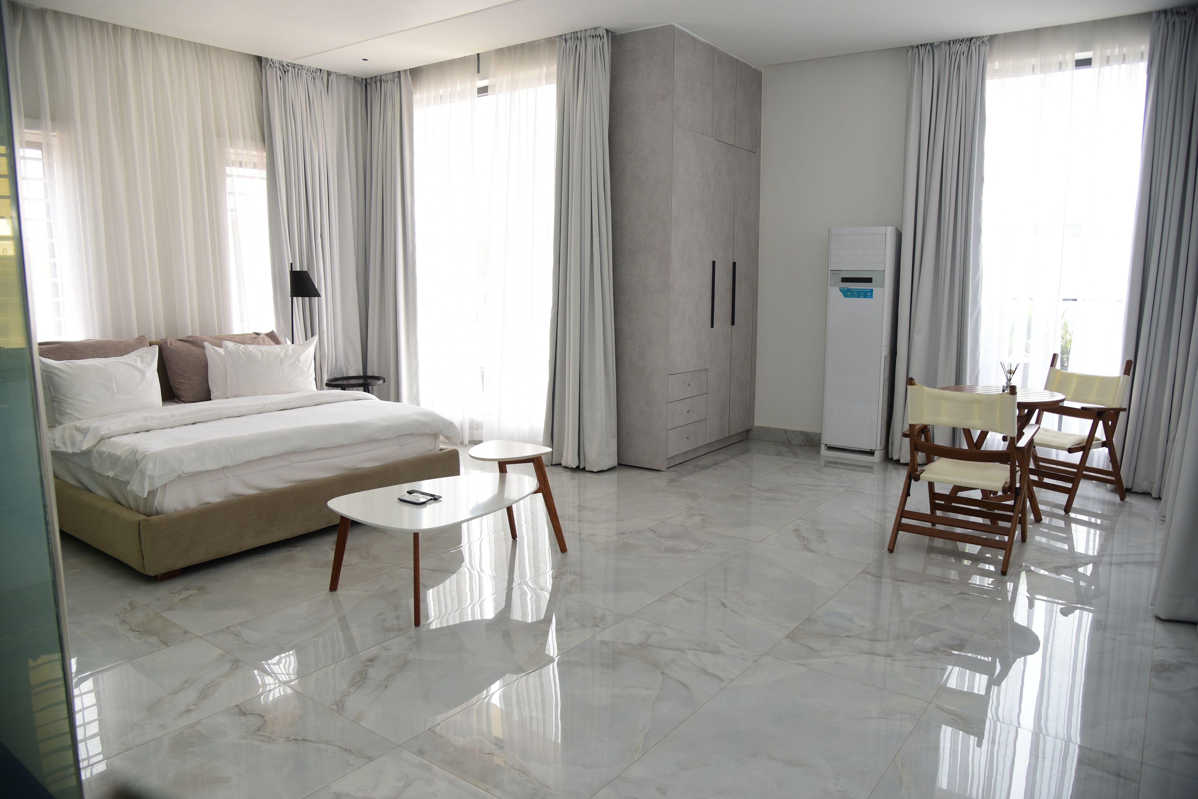A modern hotel room with a large bed, a small round table, and a seating area with chairs.